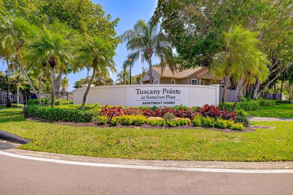 a sign for tuscany pointe in front of a building with palm trees
